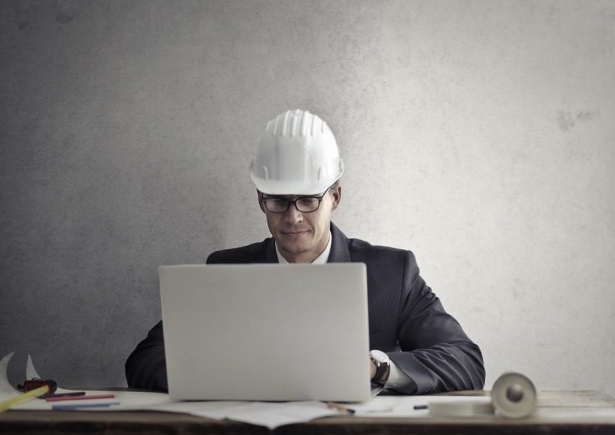  Man in suit and hard hat working on a laptop