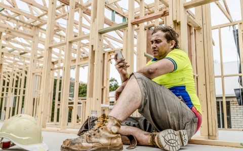 Image of a person sitting down on his phone on a work site